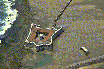 Old, white fort baths in the ocean